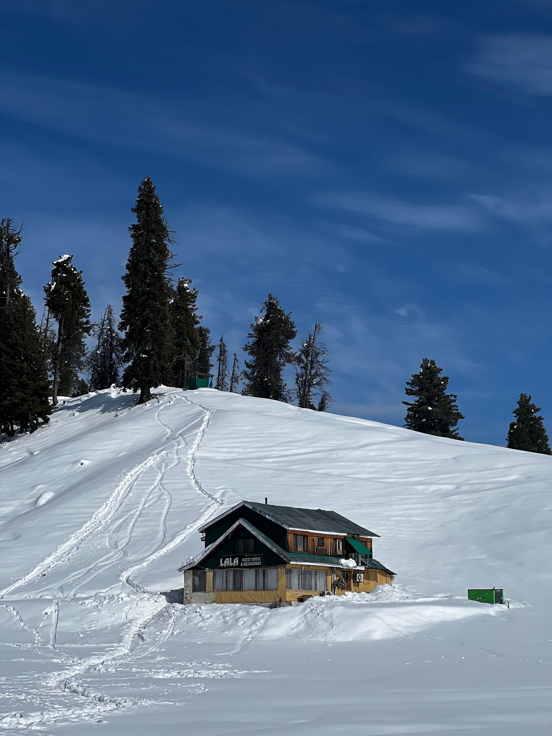 A picturesque winter cabin surrounded by snow and trees in Gulmarg's serene landscape.